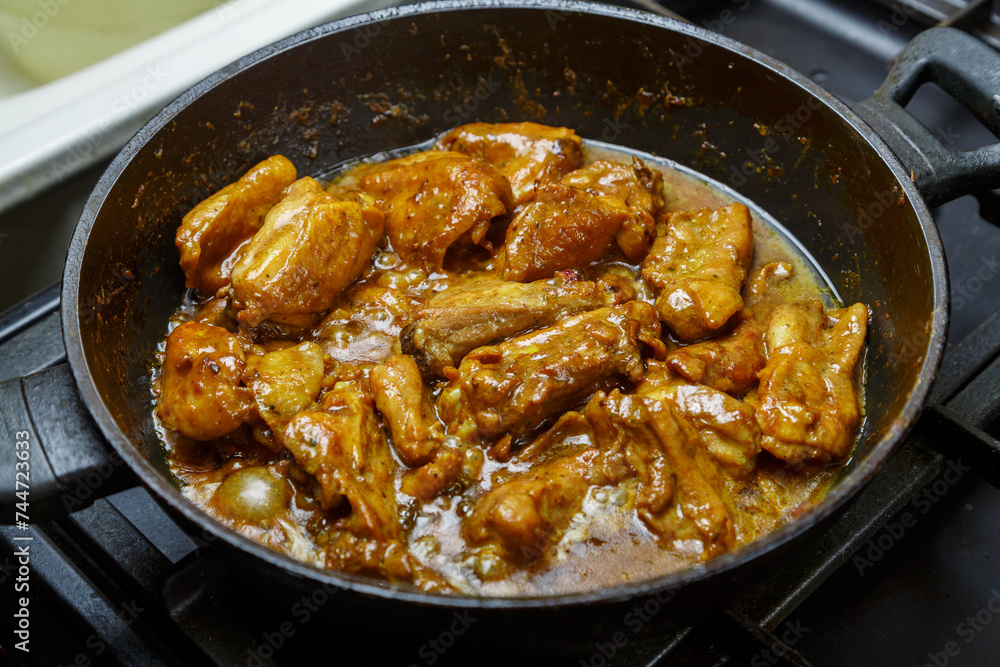 Chicken pieces in a sauce with paprika and turmeric in gravy in a frying pan Chicken pieces in a sauce with paprika and turmeric in gravy in a frying pan