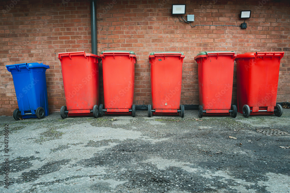 Zdjęcie Stock Row of red and one blue council wheelie rubbish bins