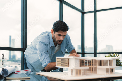 Smart civil architect engineer looking while planing design house construction with blueprint, house model and architectural equipment. Designer measuring and inspecting house model. Design. Tracery.