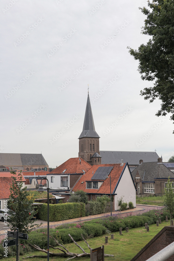 Medium wide horizontal photo of the Steenwijker toren church tower in a small city or town in Overijssel, The Netherlands. Street view with European architecture. 