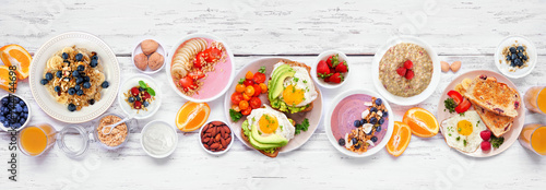 Fototapeta Naklejka Na Ścianę i Meble -  Healthy breakfast or brunch table scene on a white wood banner background. Overhead view. Avocado toast, smoothie bowls, oats, yogurt and a variety of nutritious foods.