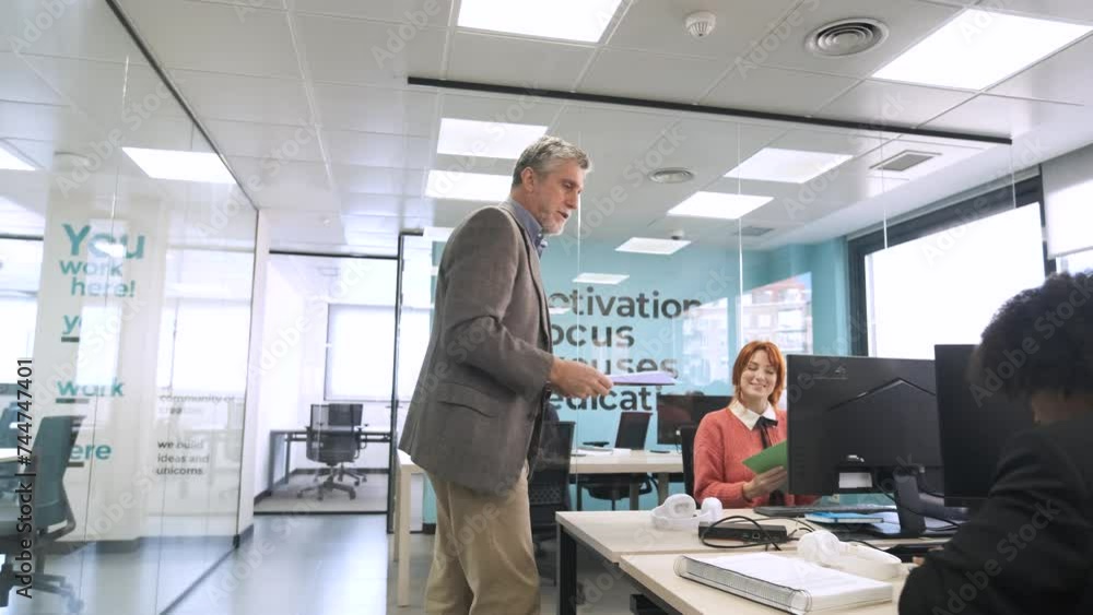 Male boss giving documents to female office workers Male boss giving documents to female office workers