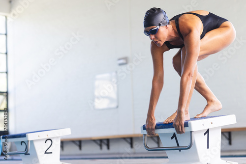 Caucasian female athlete swimmer prepares to dive into a pool at a competition photo
