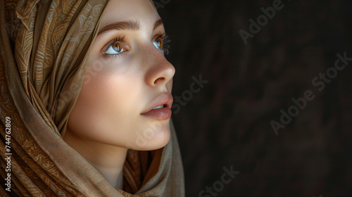 Nachdenkliches Porträt von Maria Magdalena, nach oben schauend mit braunem Kopftuch und Augen sowie Platz für Text photo