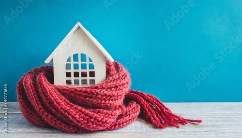 home in a knitted scarf on a blue background concept of the heating system in a winterized house photo