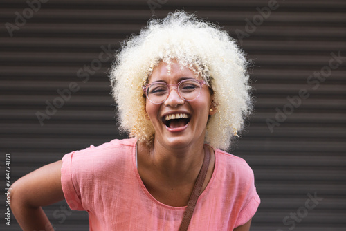 Young biracial woman laughs joyfully in the city against a striped background