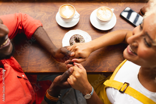 An African American man proposes to a biracial woman at a cozy cafe photo