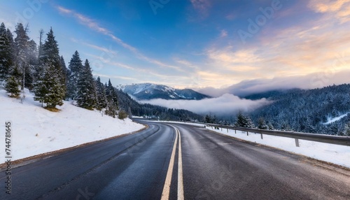 asphalt road in the middle of high mountains covered with fog and clouds at dusk american winter landscape of a mountainous area covered with fir forest