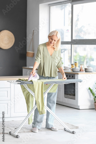 Happy mature woman ironing ...