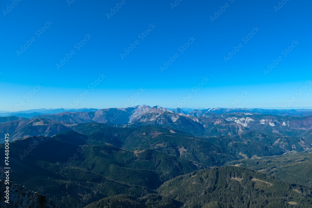 Fototapeta premium Scenic view from mount Hohe Veitsch in Mürzsteg Alps, Styria, Austria. Looking at mountain range Hochschwab in distance. Alpine valley, forest and hills in remote Austrian Alps. Wanderlust in autumn