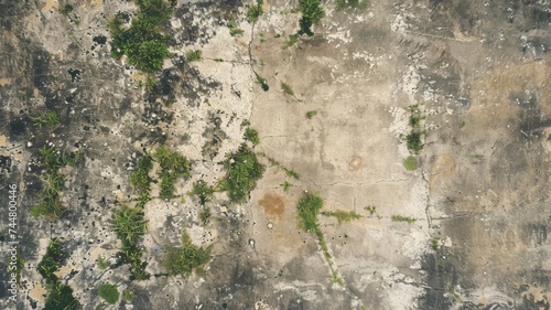 Aerial view of a rugged terrain with sparse greenery, showcasing a mix of natural textures and earthy tones.