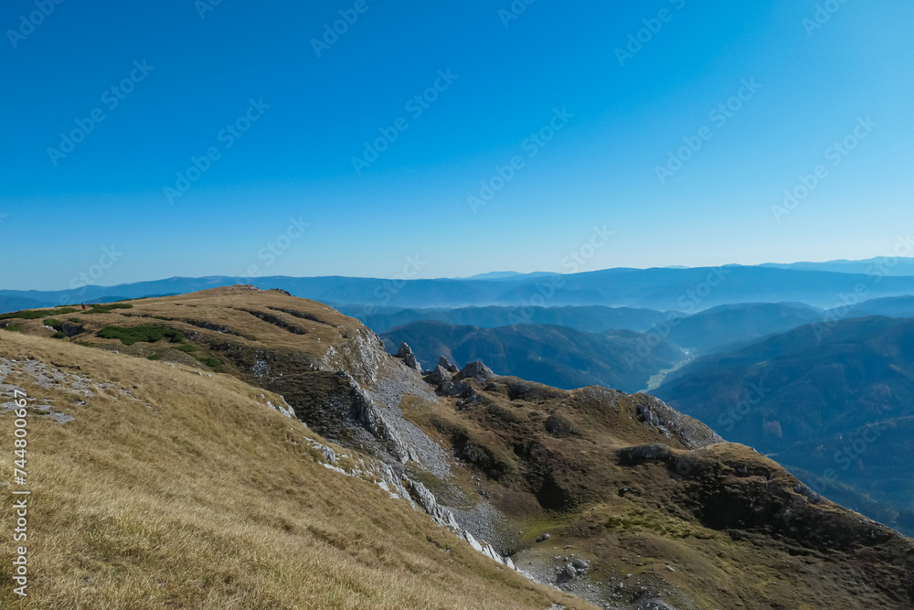 Golden alpine meadow on the way to mount Hohe Veitsch in Mürzsteg Alps, Styria, Austria. Panoramic view of mountain ridges in remote Austrian Alps. Wanderlust in autumn. Tranquil serene atmosphere