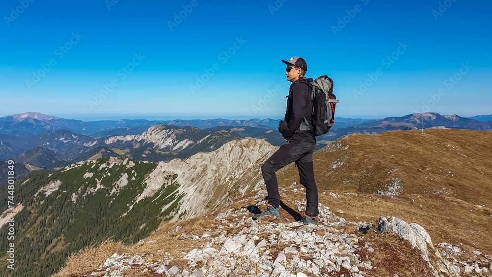 Obraz premium Hiker man on edge of steep cliff on top of mountain peak Hohe Veitsch, Mürzsteg Alps, Styria, Austria. Idyllic hiking trail in alpine terrain. Wanderlust remote Austrian Alps in autumn. Rock formation