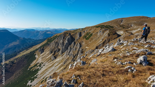 Hiker man on edge of steep cliff on top of mountain peak Hohe Veitsch, Mürzsteg Alps, Styria, Austria. Idyllic hiking trail in alpine terrain. Wanderlust remote Austrian Alps in autumn. Rock formation photo