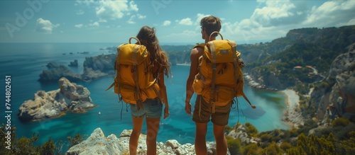 a man and a woman with backpacks are standing on top of a mountain overlooking the ocean photo