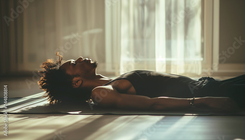 Handsome yoga adept african american man while he meditates in shavasana pose doing breathing exercises. Active people, Oriental practices in common life, relaxing or mental health concept ima