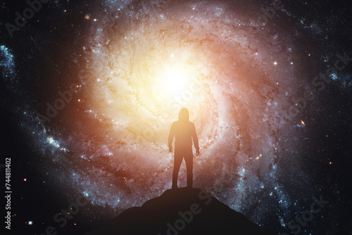 Silhouette of a man standing on the top of a mountain against the background of the galaxy. Elements of this image furnished by NASA