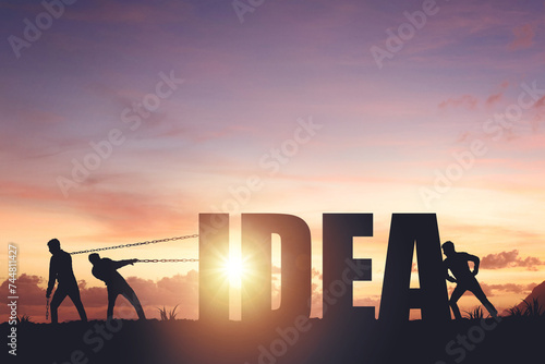 Silhouettes of people drawing the word IDEA on a sunset background, business concept