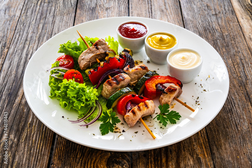 Meat skewers - grilled meat with vegetables on wooden background 