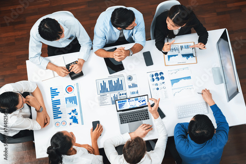 Top view analyst team utilizing BI Fintech to analyze financial data at table in meeting room. Analytic BI dashboard power on paper for business insight and strategic marketing planning. Prudent