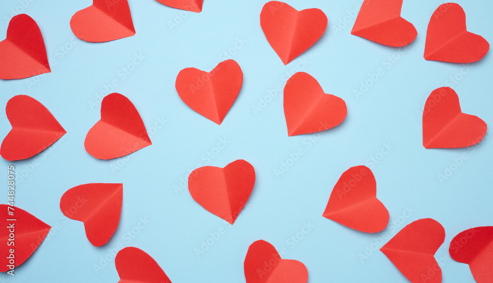 Red paper hearts on a blue background, top view Red paper hearts on a blue background, top view