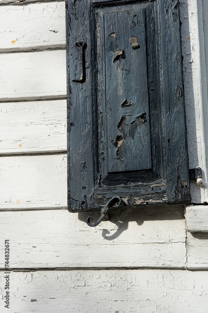 Weathered shutter on clapboard wall