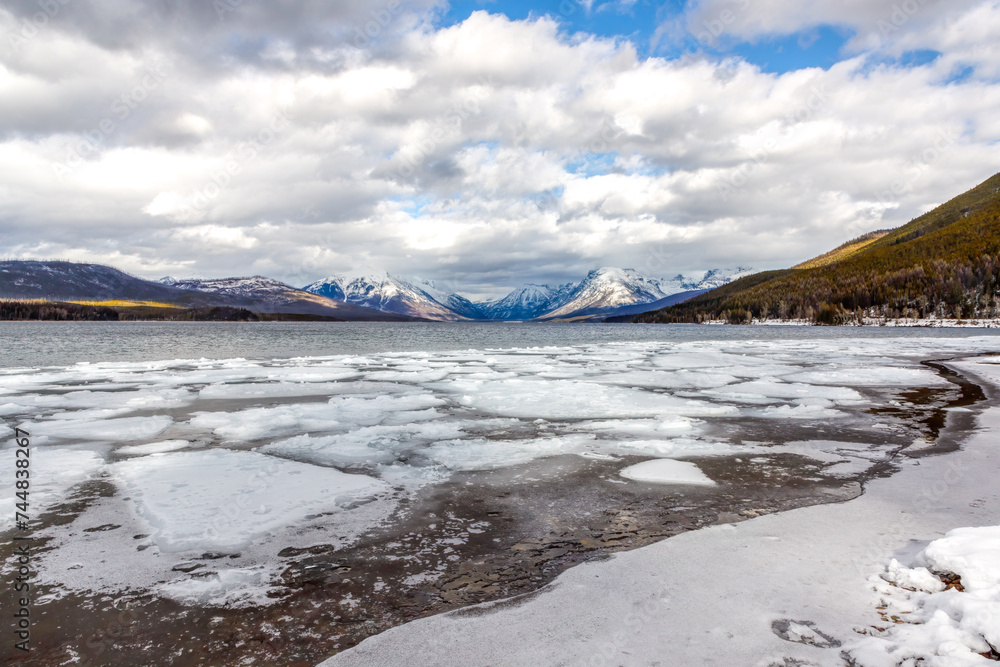 Winter icy scene of Lake McDonald, Glacier National Park, Montana with distant snowy peaks in background Winter icy scene of Lake McDonald, Glacier National Park, Montana with distant snowy peaks in background