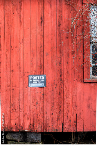 Weathered red wood siding with posted, no trespassing sign photo