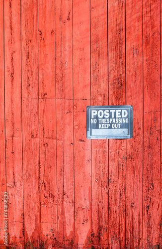 Weathered red wood siding with posted, no trespassing sign
