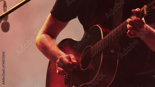 guitarist plays acoustic guitar at a concert on the stage photo