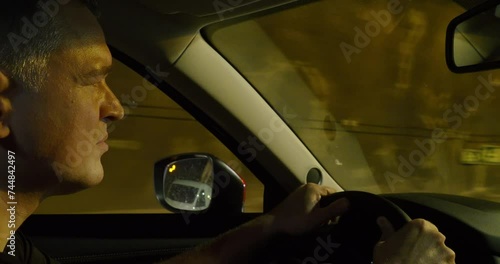 Close up of a Caucasian driver face intermittently lit by the lights inside a tunnel photo