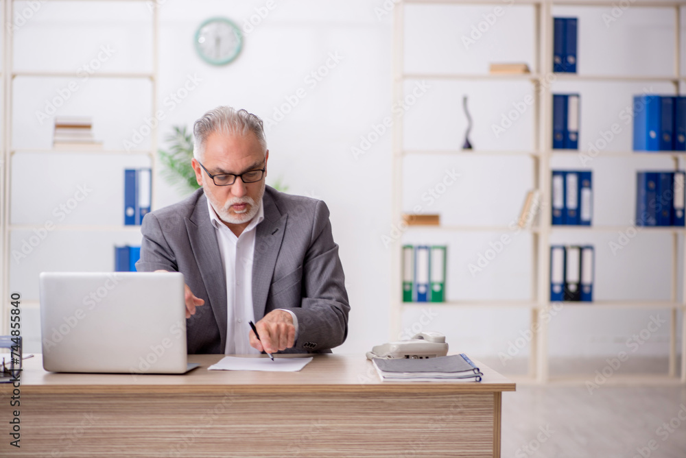 Old male employee working in the office Old male employee working in the office