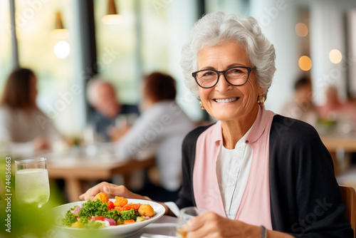 A senior woman enjoying a healthy meal in a restaurant with a joyful smile.