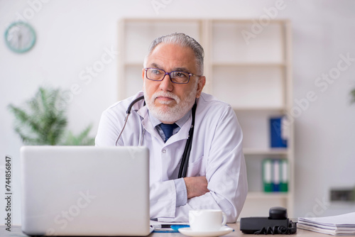 Old male doctor sitting in the clinic
