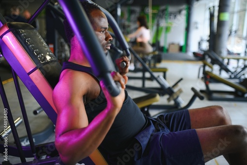 Motivated young black sportsman having workout on rowing machine © Serhii