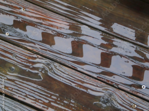 Reflections in rain puddles on old wooden deck (ID: 744859447)