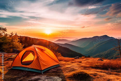 Camping tent on a hill during sunset with mountainous backdrop.