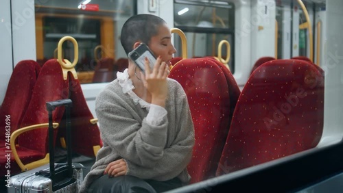 Tired tourist calling mobile phone in train. Short hair woman talking smartphone photo
