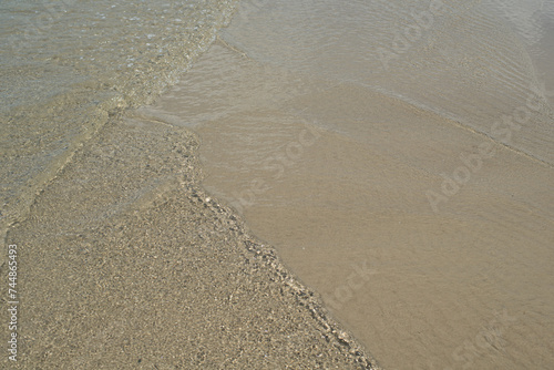 At the beach, gentle ripples caress sand and water, creating a serene and soothing atmosphere
