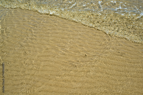 At the beach  gentle ripples caress sand and water  creating a serene and soothing atmosphere