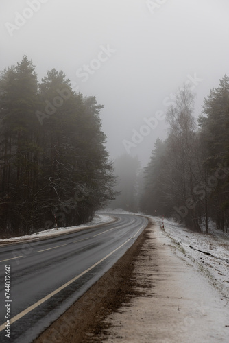 beautiful snow-covered road during fog in winter © rsooll