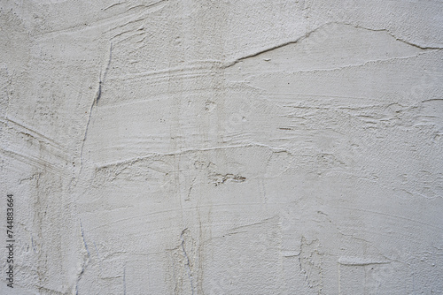 A gray cement wall with carelessly smoothed layers of white plaster and lots of scratches and chips. Vector cement texture background