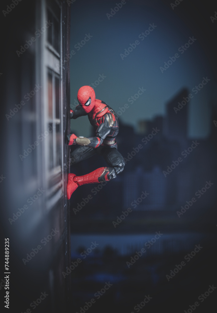 Obraz premium NEW YORK USA, FEB 25 2024: friendly neighborhood spiderman crawling on the side of a building - Hasbro action figure