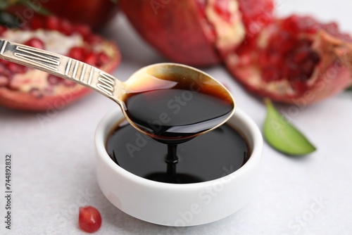 Tasty pomegranate sauce on light table, closeup