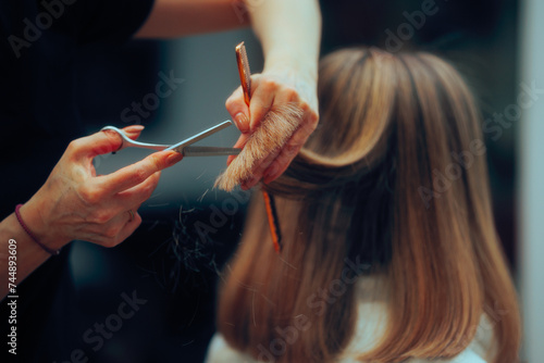 Woman Having her Ends Trimmed in a Hair Salon. Client cutting her straight blonde hair shorter at the salon 
