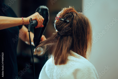 Woman Sitting in Hair Salon Having Her Hair Professionally Done. Hairstylist working on the look of a client with hairdryer and brush 
