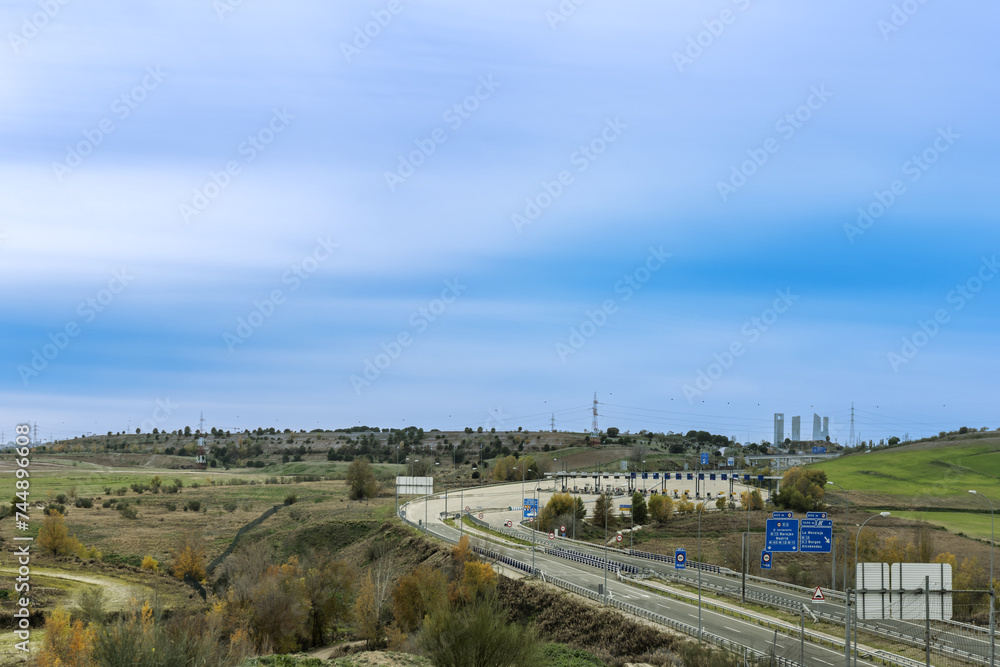 Peak area of a highway access to the city of Madrid with part of the skyline in the background