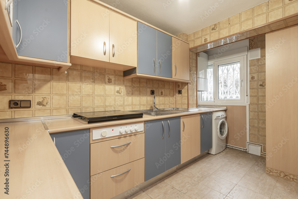 Kitchen furnished with light wood furniture combined with pale blue, aluminum handles, wood-colored countertop and integrated white appliances. Kitchen furnished with light wood furniture combined with pale blue, aluminum handles, wood-colored countertop and integrated white appliances.