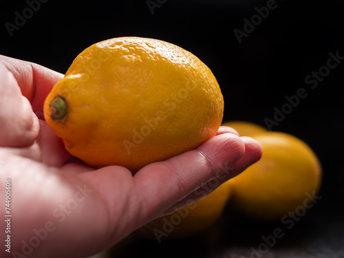 Fresh Lemon Held in Hand Over Dark Background