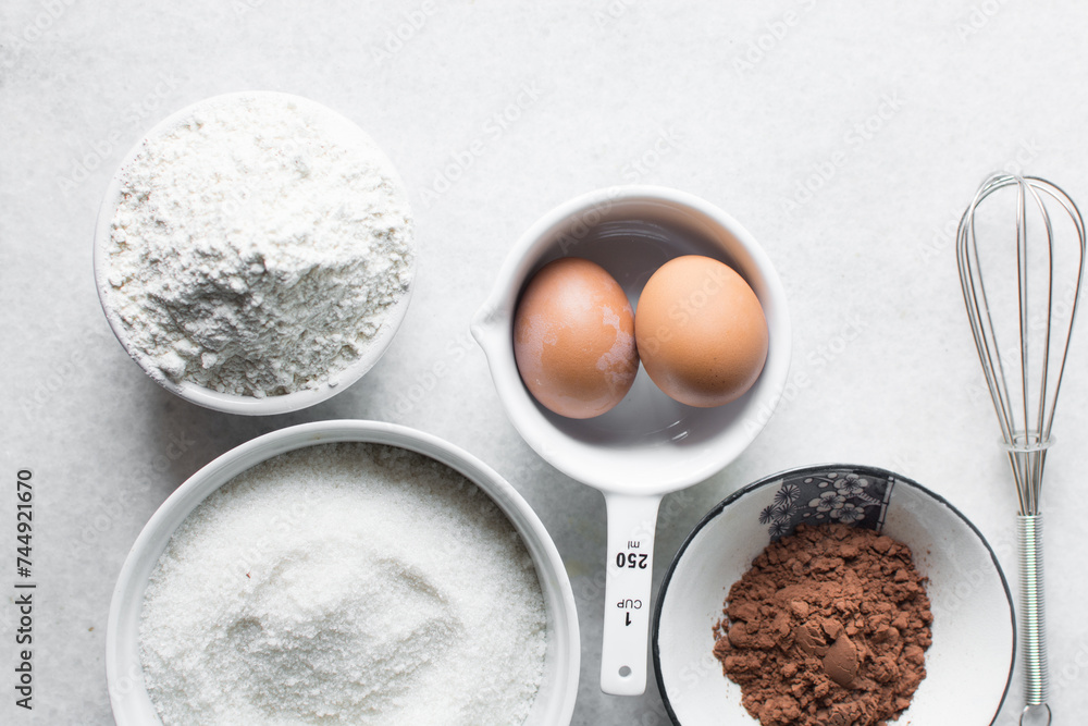 mise en place of ingredients for making brownies, top view of sugar, eggs, butter, flour cocoa powder on a marble table, process of making brownies mise en place of ingredients for making brownies, top view of sugar, eggs, butter, flour cocoa powder on a marble table, process of making brownies
